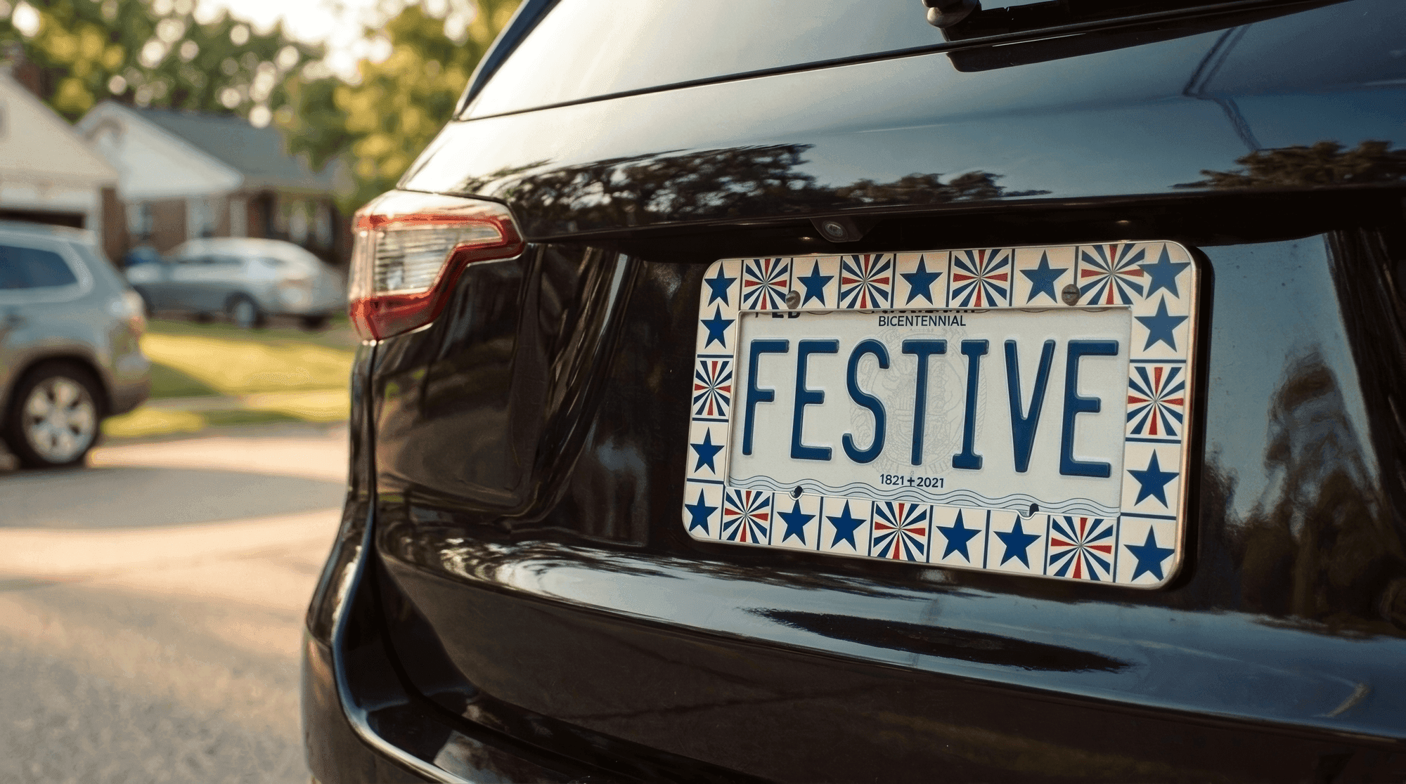 A Festive Frames kit snapped onto the license plate of a parked car at golden hour, red, white and blue star and firework tiles around the border